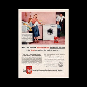 May include: A vintage advertisement for Dash laundry detergent featuring a woman and children in a kitchen with a white Bendix Duomatic washing machine. The ad text reads "What a hit! This new Bendix Duomatic both washes and dries... and Dash's low suds are just made-to-order for it!" and "Only Dash is packed in every Bendix Automatic Washer!"