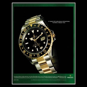 May include: A Rolex GMT-Master II watch with a black dial and gold and silver-tone metal band. The watch face displays the date and multiple time zones. The advertisement includes the text: "It takes 216 individual operations to make a Rolex tick."