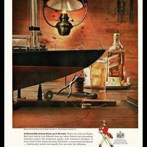 May include: A vintage advertisement for Johnnie Walker Red Label Scotch Whisky. The ad features a still life of a bottle of scotch, a glass of ice, and a model sailboat on a wooden table. The text reads "Craftsmanship always shows up in the taste. That's why Johnnie Walker Red Label Scotch is so different from any other. Patient and painstaking craftsmen protect the traditional quality with unhurried attention to every detail of fine whisky blending. The result - a consistently rare flavour ... traditionally mellow and smooth. You can taste the difference. Johnnie Walker Red Label Scotch Whisky. Blended Scotch Whisky, 86.8 Proof. Imported by Canada Dry Corporation, New York, N.Y."