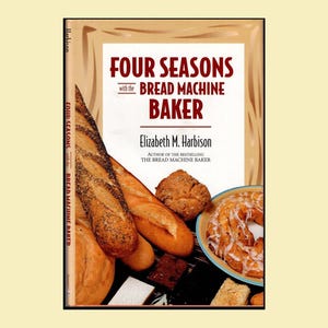 May include: A cookbook titled Four Seasons with the Bread Machine Baker by Elizabeth M. Harbison. The cover features a variety of baked goods including a long baguette, a round loaf, and a glazed pastry on a plate against a tan background.
