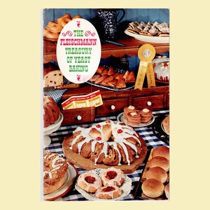 May include: A vintage cookbook cover titled The Fleischmann Treasury of Yeast Baking, featuring a variety of baked goods including a glazed ring cake, rolls, pancakes, and pastries arranged on a blue and white checkered tablecloth and wooden shelves.
