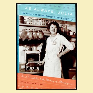 May include: Book cover featuring a vintage photograph of Julia Child in her kitchen. The book title is "AS ALWAYS, JULIA" with the subtitle "The Letters of JULIA CHILD & AVIS DEVOTO." The cover also includes the text "Food, Friendship & the Making of a Masterpiece."