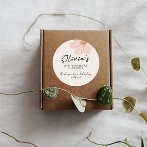 以下が含まれることがあります： ピンクの花と「Olivia's 9th Birthday 6.23.20XX Thank you for celebrating with us!」というテキストが書かれた丸い白いステッカー