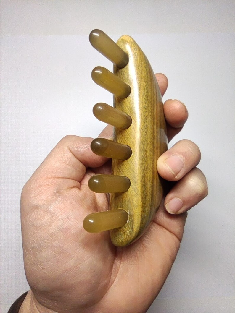 May include: A wooden comb with five translucent brown teeth. The comb is curved and has a wood grain pattern.