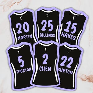 May include: Six black jersey stickers with white and light purple accents. Each jersey displays a different number and last name: 20 Martin, 25 Billings, 15 Hayes, 5 Thorton, 2 Chen, and 22 Burton. The jerseys have a small logo at the top.