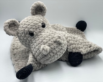May include: A gray crocheted hippopotamus baby blanket with black crocheted eyes and feet.