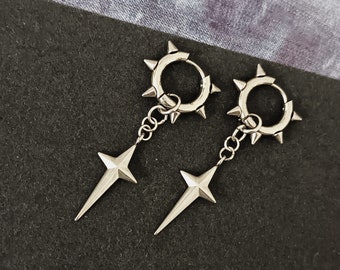May include: A pair of silver earrings with a star-shaped pendant and a circular hoop with spikes. The earrings are on a black background.