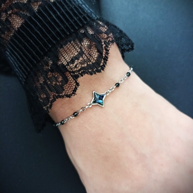 May include: A silver chain bracelet with black beads and a blue star-shaped charm.