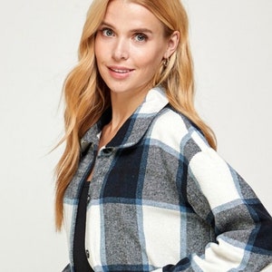 May include: A long-sleeved flannel shirt with a white and blue plaid pattern. The shirt has a collared neckline and button closure.