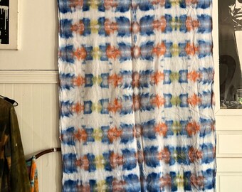 Peut inclure: Un tissu en coton blanc avec un motif tie-dye bleu, orange et jaune. Le tissu a une bordure frangée.