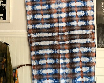 Peut inclure: Une tenture murale en tissu tie-dye bleu, marron et blanc avec des franges en bas.