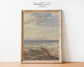 Könnte beinhalten: Ein Vintage-Gemälde, das eine Meereslandschaft mit einem bewölkten Himmel und einem Sandstrand mit Wellen, die an das Ufer schlagen, zeigt. Das Gemälde ist in einem hellen Holzrahmen gerahmt.