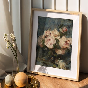 May include: A framed painting of a bouquet of pink roses in a vase. The roses are arranged in a cluster and have a soft, romantic feel. The painting is set against a blue background and has a vintage aesthetic.