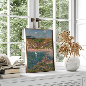 May include: A framed painting of a seascape with a sailboat in the water and a green hillside in the background.