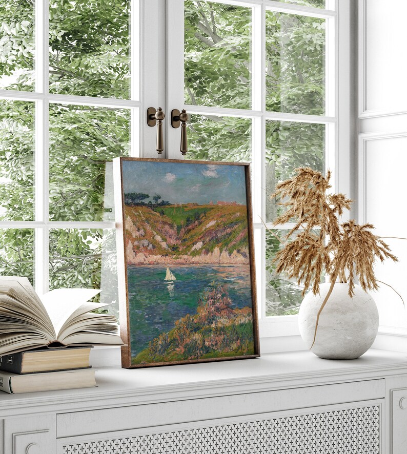 May include: A framed painting of a seascape with a sailboat in the water and a green hillside in the background.