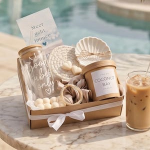 Könnte beinhalten: Eine Geschenkbox mit einem Glastrinkbecher mit Bambusdeckel und der Aufschrift good vibes only, einem runden Untersetzer, einer muschelförmigen Schale, einem beigen Haargummi, einem goldenen Armband, herzförmigen Wachsschmelzen und Coconut Bay Wachs.