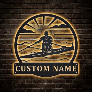 May include: Black metal silhouette of a person rowing a boat with a sun and clouds in the background. The text "CUSTOM NAME" is below the silhouette.