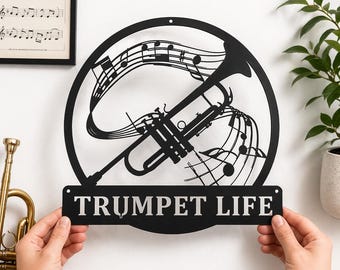 Może przedstawiać: Czarna metalowa grafika ścienna przedstawiająca trąbkę i nuty w okrągłej ramie. Słowa "TRUMPET LIFE" są wyświetlane na prostokątnej tabliczce pod trąbką. W tle widoczny jest oprawiony wydruk "JAZZ is my life".