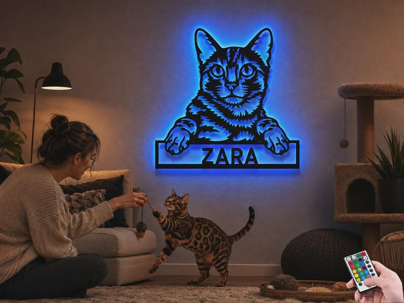May include: A wall-mounted cat-shaped sign featuring a black silhouette of a cat with glowing blue LED backlighting. The design includes a rectangular nameplate at the bottom with the name ZARA in bold, capital letters, illuminated in blue.
