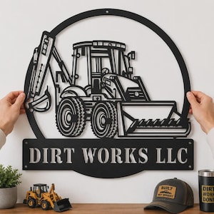 May include: A circular black metal wall sign featuring a detailed cutout of a backhoe loader. Below the circular frame, a rectangular metal plate displays the text DIRT WORKS LLC in bold, capitalized, stencil-style lettering.