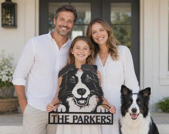 May include: A black metal sign featuring a cutout of a border collie dog face with paws resting on a rectangular nameplate that reads THE PARKERS in bold capital letters. The sign is held by a family standing in front of their home.