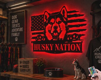 Könnte beinhalten: Ein schwarzes Metall-Wandschild mit der Silhouette eines Husky-Kopfes, zentriert über einem abgenutzten amerikanischen Flaggendesign, beleuchtet durch eine rote LED-Hintergrundbeleuchtung. Das Schild trägt den Text HUSKY NATION in fetten Großbuchstaben.