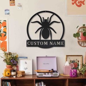 May include: Black metal wall decor featuring a spider silhouette inside a circle with the text "CUSTOM NAME" below.