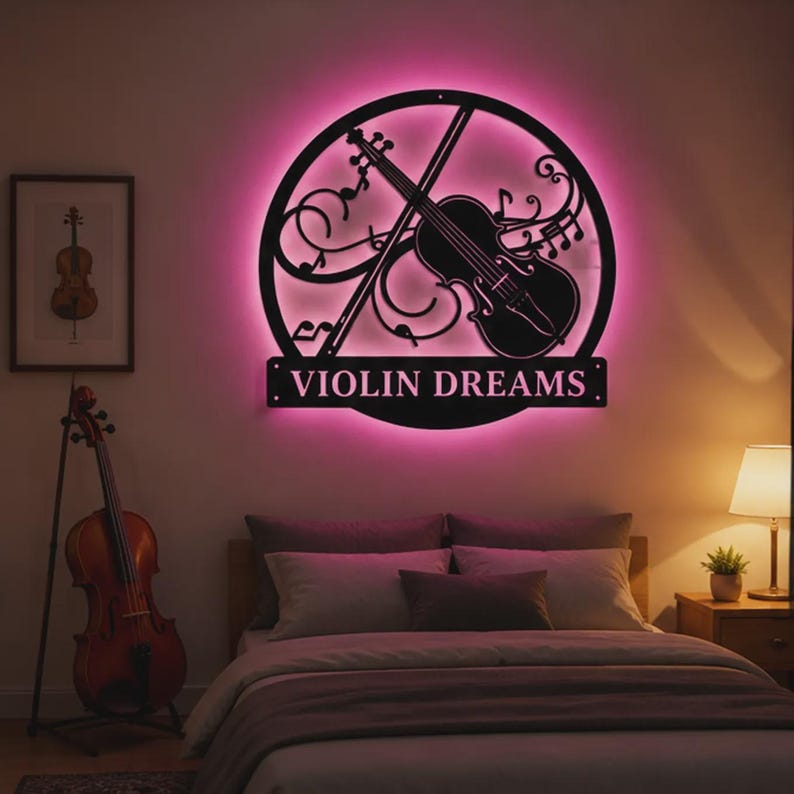 Może przedstawiać: Czarna metalowa dekoracja ścienna z skrzypcami i nutami w okrągłej ramie, podświetlona na r&oacute;żowo. Poniżej widnieje napis "VIOLIN DREAMS". Widoczny jest r&oacute;wnież oprawiony wydruk skrzypiec oraz skrzypce na stojaku.