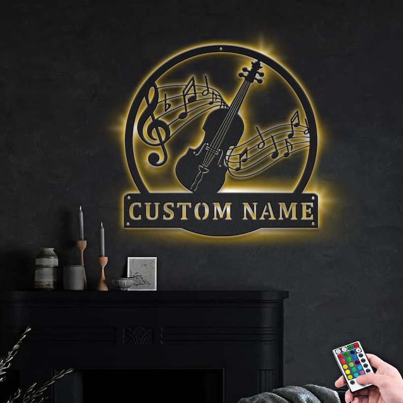 May include: A black metal wall sign with a silhouette of a violin and musical notes. The sign is illuminated with warm white LED lights and has a gold inscription that reads "CUSTOM NAME".