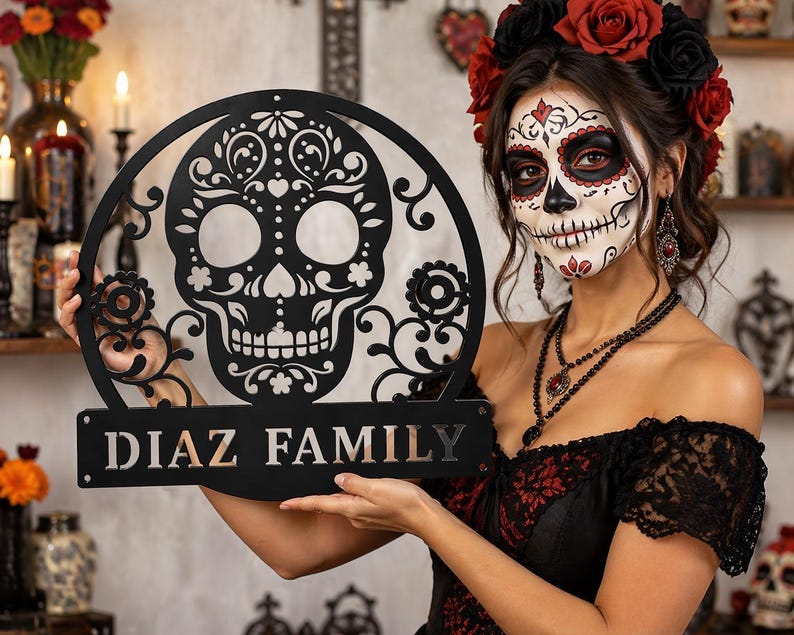 May include: A black metal Dia de los Muertos-themed family sign featuring a decorative skull design. The sign has the family name "DIAZ FAMILY" in bold letters. The skull is surrounded by floral and ornamental details.