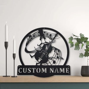 May include: Black metal wall art featuring a silhouette of a violin player with musical notes and a customizable nameplate. The nameplate reads "CUSTOM NAME".