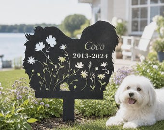 May include: A black metal garden stake shaped like a dog silhouette, featuring cut-out floral designs and the engraved text "Coco" above the years "2013-2024". The stake has a vertical post for insertion into the ground.