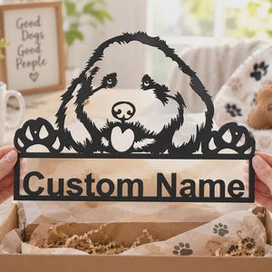 May include: A black metal sign featuring a stylized dog head silhouette with paw prints on either side and a rectangular base with the text Custom Name cut out in a bold sans-serif font, presented in a cardboard gift box with tissue paper.