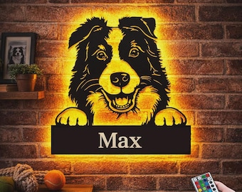 May include: A wall-mounted LED sign featuring a black silhouette of a dog with a glowing yellow backlight. Below the dog is a rectangular black plaque with the name Max in white text. A remote control is included to adjust the light settings.