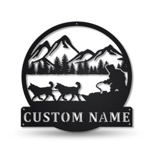 May include: Black metal wall art featuring a silhouette of a dog sledding team with a musher in a snowy mountain landscape. The art includes the text "CUSTOM NAME".
