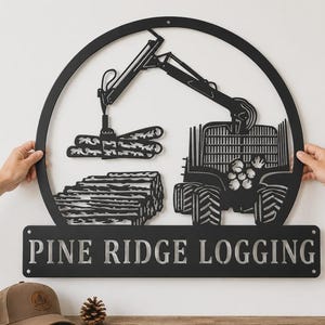 May include: A circular black metal wall sign featuring a cutout design of a logging machine lifting logs above a stack of timber. Below the circular frame is a rectangular panel with the text PINE RIDGE LOGGING in bold, capital letters.