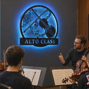 Puede incluir: Un letrero de pared circular de metal negro con la silueta de un viol&iacute;n y un arco, notas musicales y el texto ALTO CLASS. El letrero est&aacute; iluminado por una luz LED azul de fondo y se encuentra montado en una pared oscura sobre unos violinistas.
