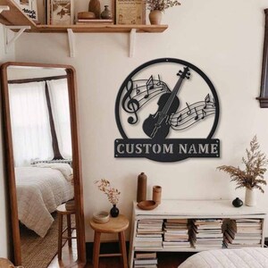 May include: Black metal wall art featuring a violin with musical notes and the text "CUSTOM NAME".
