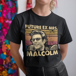 May include: Black t-shirt with a vintage-style graphic featuring a man with sunglasses and the text "FUTURE EX MRS. MALCOLM".