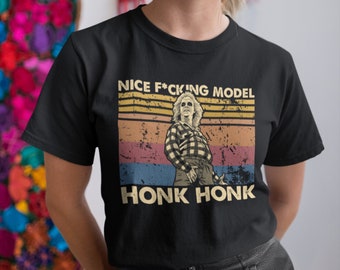 May include: Black t-shirt with a vintage-style graphic featuring a person in a plaid shirt and the text "NICE F*CKING MODEL HONK HONK".