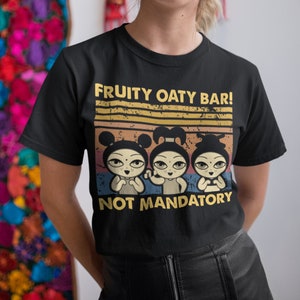 Może przedstawiać: Czarny T-shirt z grafiką w stylu vintage przedstawiającą trzy kreskówkowe dziewczyny i tekst "FRUITY OATY BAR! NOT MANDATORY".
