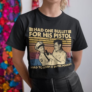 May include: A black t-shirt with a vintage-style graphic featuring two men in uniform. The graphic says "Had one bullet for his pistol, had to keep it in his pocket".