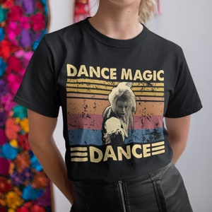 Pode incluir: Camiseta preta com um gráfico de estilo vintage de uma pessoa dançando com o texto "Dance Magic" e "Dance" em uma fonte retrô.