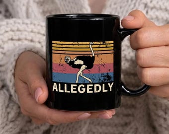 Könnte beinhalten: Schwarze Keramik-Tasse mit Retro-Design. Sie zeigt eine Straußen-Illustration und das Wort "ALLEGEDLY" in Weiß. Der Hintergrund hat horizontale Streifen in Orange, Gelb, Blau und Rosa. Die Tasse hat einen schwarzen Henkel.