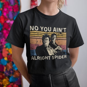Puede incluir: Una camiseta negra con un gráfico de estilo vintage de dos hombres. El gráfico presenta un fondo de puesta de sol con el texto "NO YOU AIN'T ALRIGHT SPIDER".
