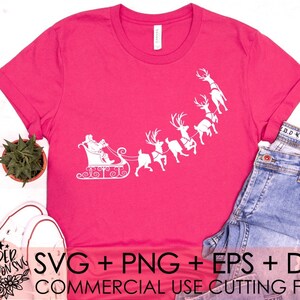 May include: A pink t-shirt with a white design of Santa Claus in a sleigh pulled by reindeer. The text "SVG + PNG + EPS + DXF COMMERCIAL USE CUTTING FILES" is at the bottom of the shirt.