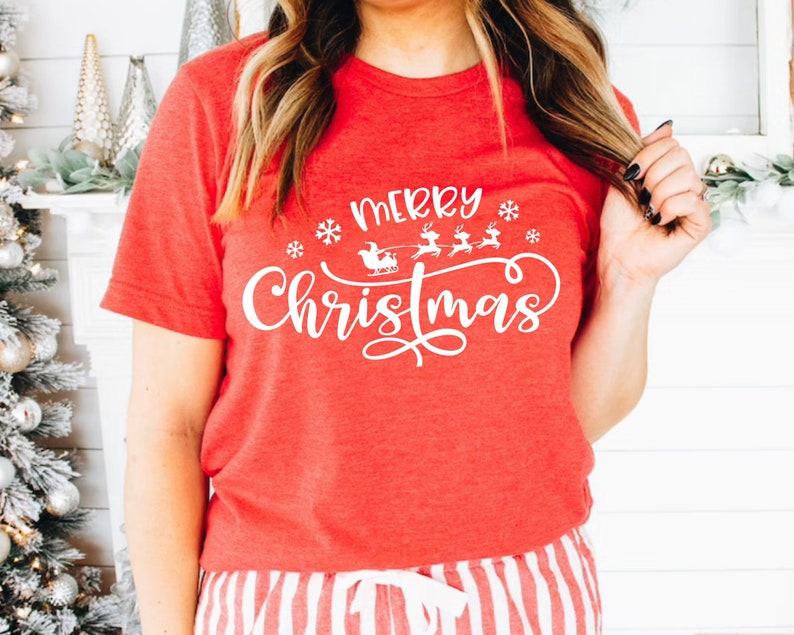 May include: Red t-shirt with white text that says "Merry Christmas" with a graphic of Santa's sleigh and reindeer.