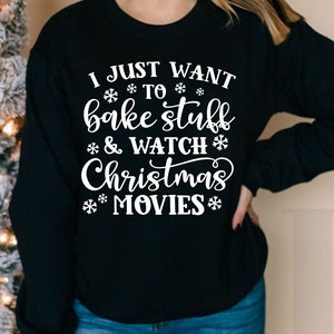 May include: Black sweatshirt with white text that reads "I just want to bake stuff & watch Christmas movies". The text is surrounded by snowflakes.