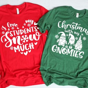 May include: Two Christmas themed t-shirts. The red shirt says "I love my students snow much" with snowflakes and hearts. The green shirt says "Christmas with my gnomes" with three gnomes and snowflakes.