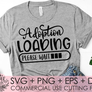 Peut inclure: Un t-shirt gris avec le texte "Adoption Loading Please Wait" et un graphique de barre de progression. Le texte est en noir et la barre de progression est remplie en noir. Le t-shirt est sur une surface blanche avec un jean bleu et une feuille verte.